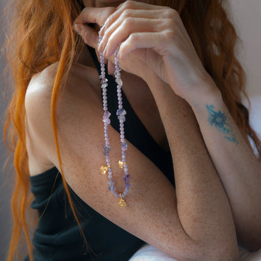 Elegante collar corto de piedra agata y cristal facetado lila, con unas flores de Zamak con baño de oro mate. Esta pieza contiene un cierre filigrana con baño de oro. Este collar es ideal para combinar con tus prendas favoritas. Modelo Pilar